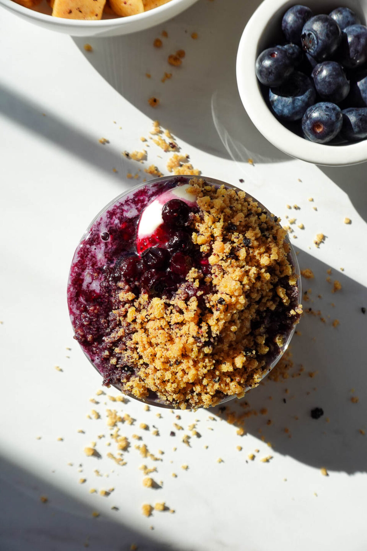 overhead shot of blueberry overnight oats topped with vegan yogurt, blueberry compote, and crushed protein cereal
