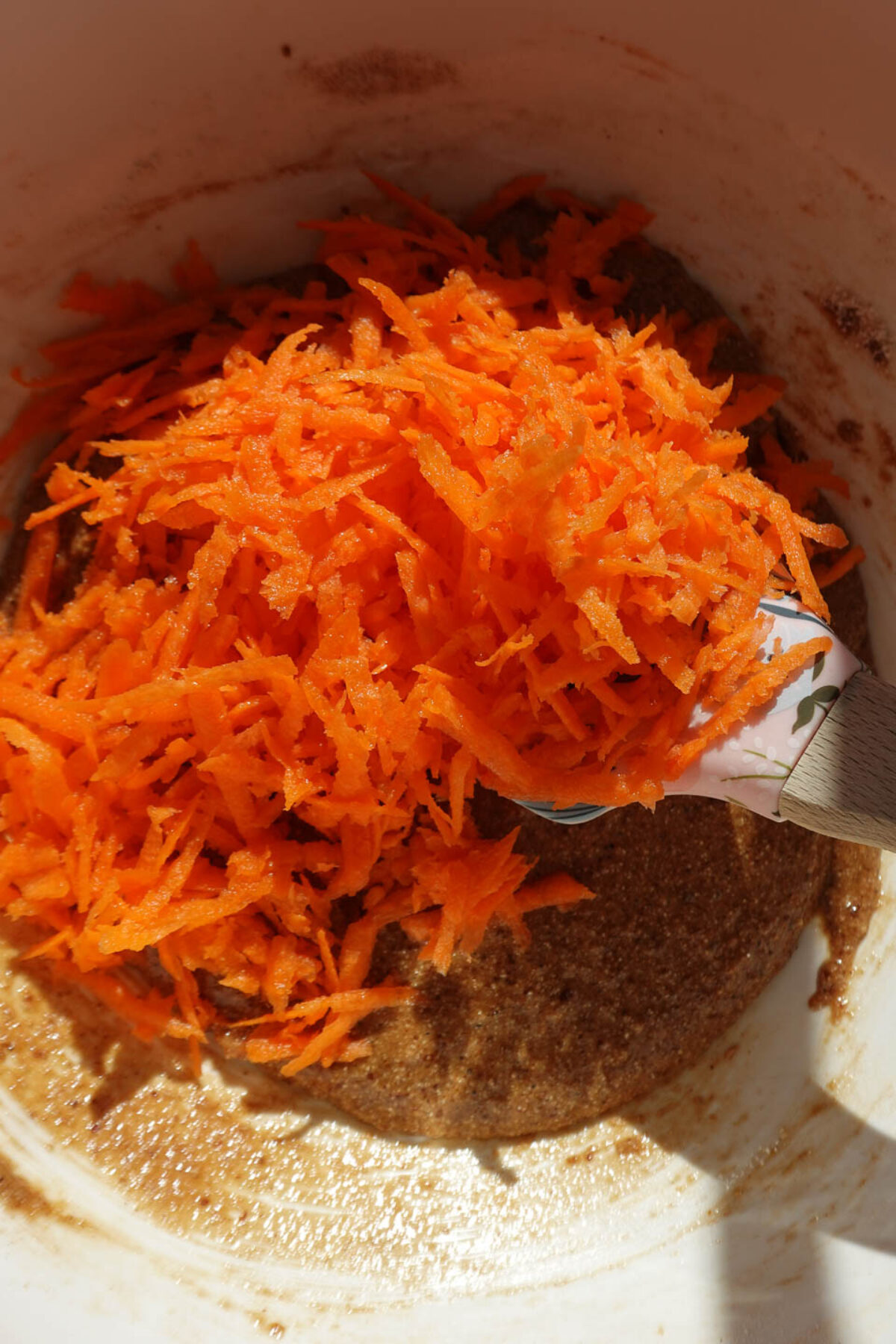 Freshly grated carrots being added to carrot cake batter