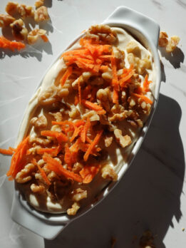 Healthy carrot cake overnight oats with grated carrots, cinnamon, nutmeg, vegan yogurt, and walnuts