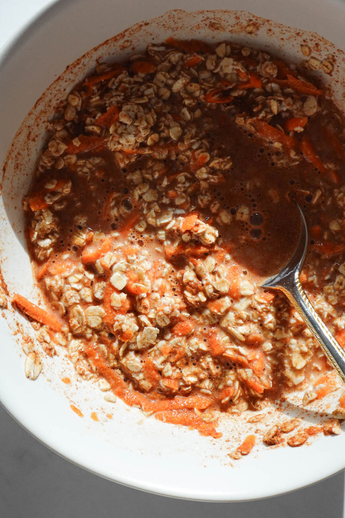 Mixing carrot cake overnight oats with oats, grated carrots, milk, and spices