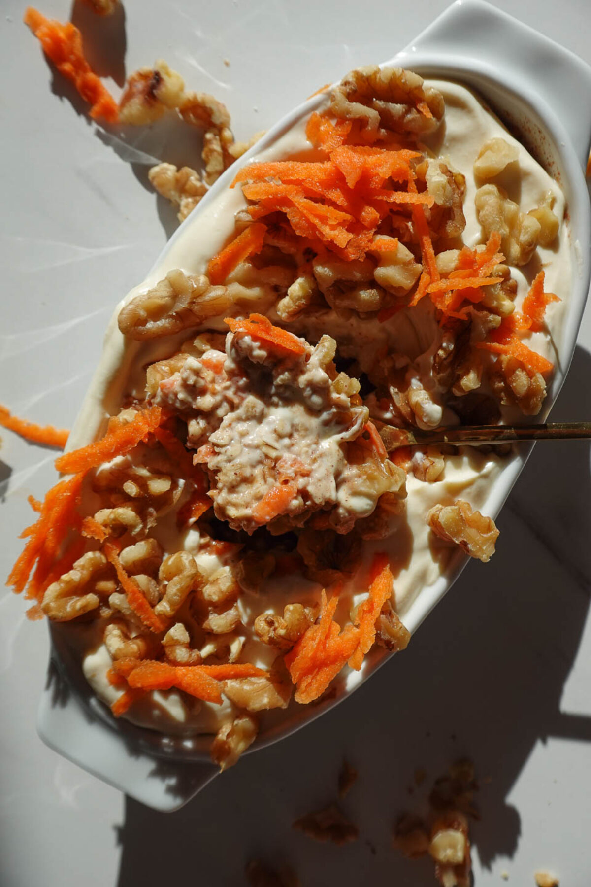 Close up of carrot cake overnight oats with creamy yogurt, walnuts, and cinnamon