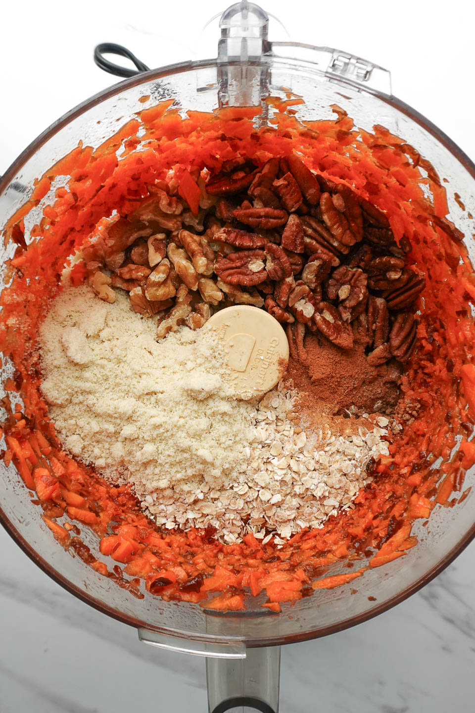 Adding walnuts, oats, pecans, and almond flour to food processor