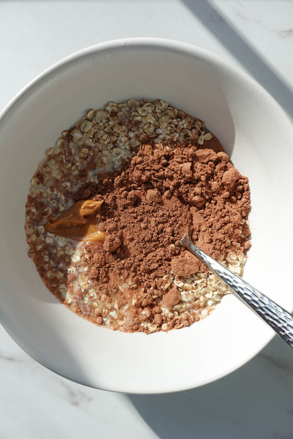 Mixing ingredients including cocoa powder and coconut milk into oats