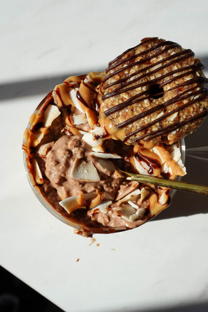 Overhead view of Samoas overnight oats drizzled with chocolate syrup, peanut butter, and topped with a samoas cookie