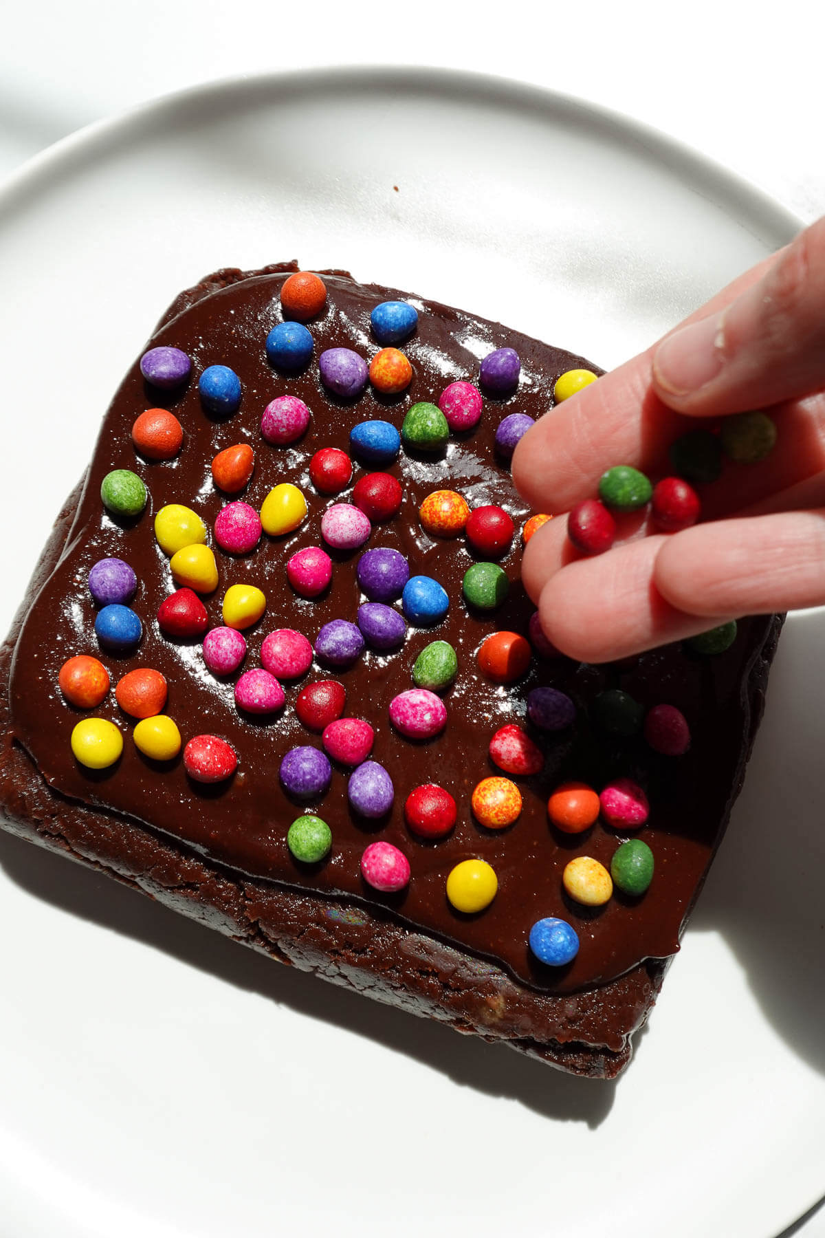 Adding sprinkles on top of no bake cosmic brownies.