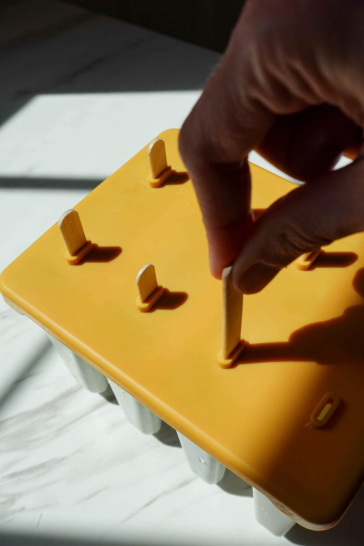 Inserting sticks into ice cream molds before freezing.