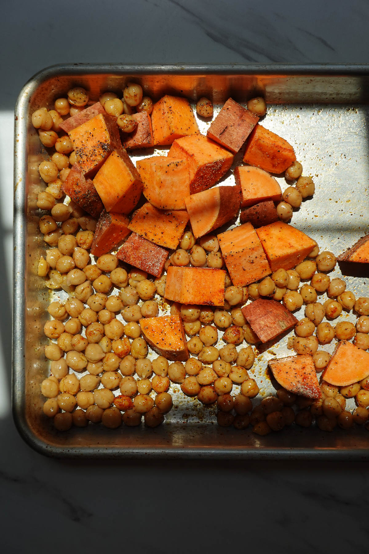 Roasting sweet potatoes and chickpeas on a baking sheet.