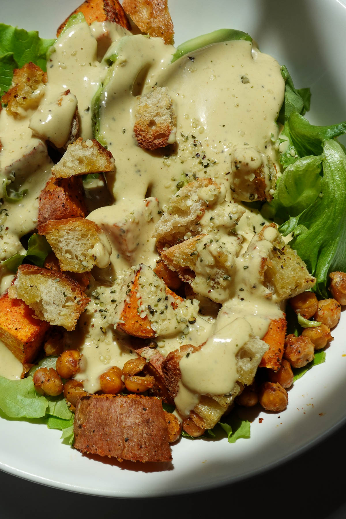 Sweet potato chickpea salad in a bowl topped with vegan honey mustard dressing.