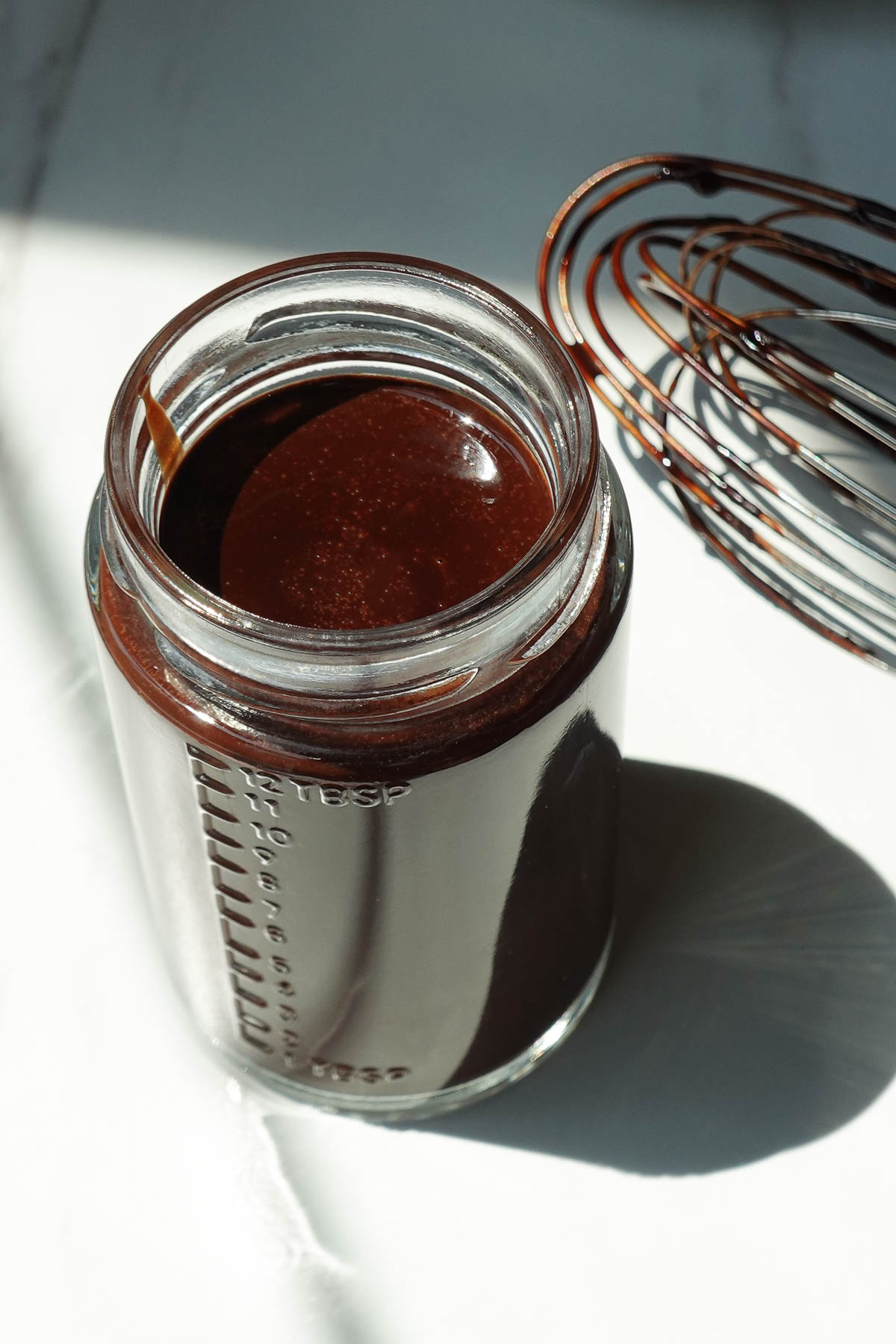 Freshly made chocolate syrup cooling in a glass jar before thickening.