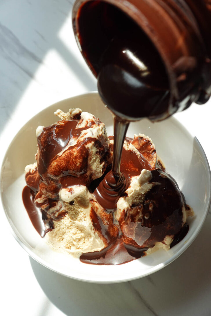 Drizzling homemade chocolate syrup on top of ice cream.