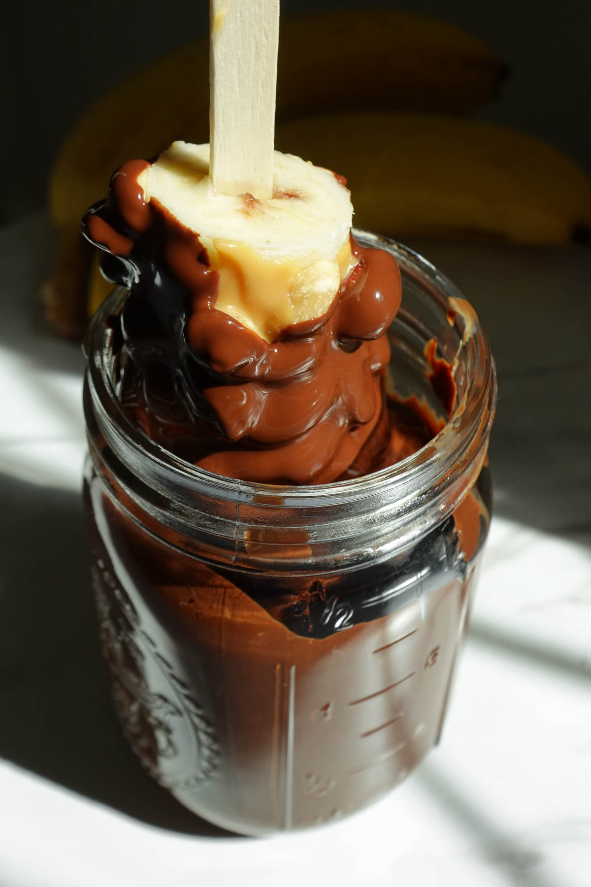 Dipping frozen banana pops into melted dark chocolate.
