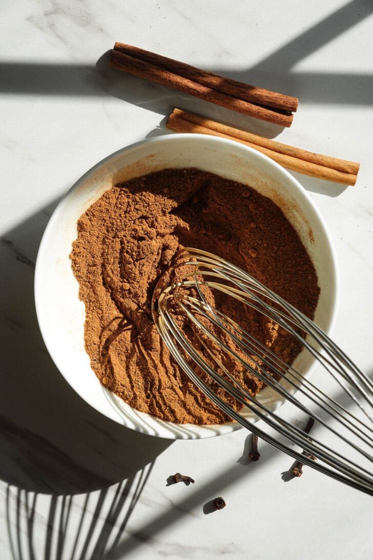 Ground spices being whisked together to make homemade pumpkin pie spice.