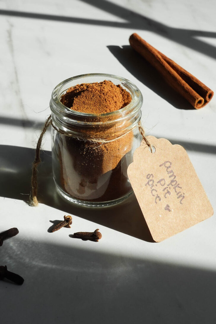 Homemade pumpkin pie spice in a small glass jar with a handwritten label.