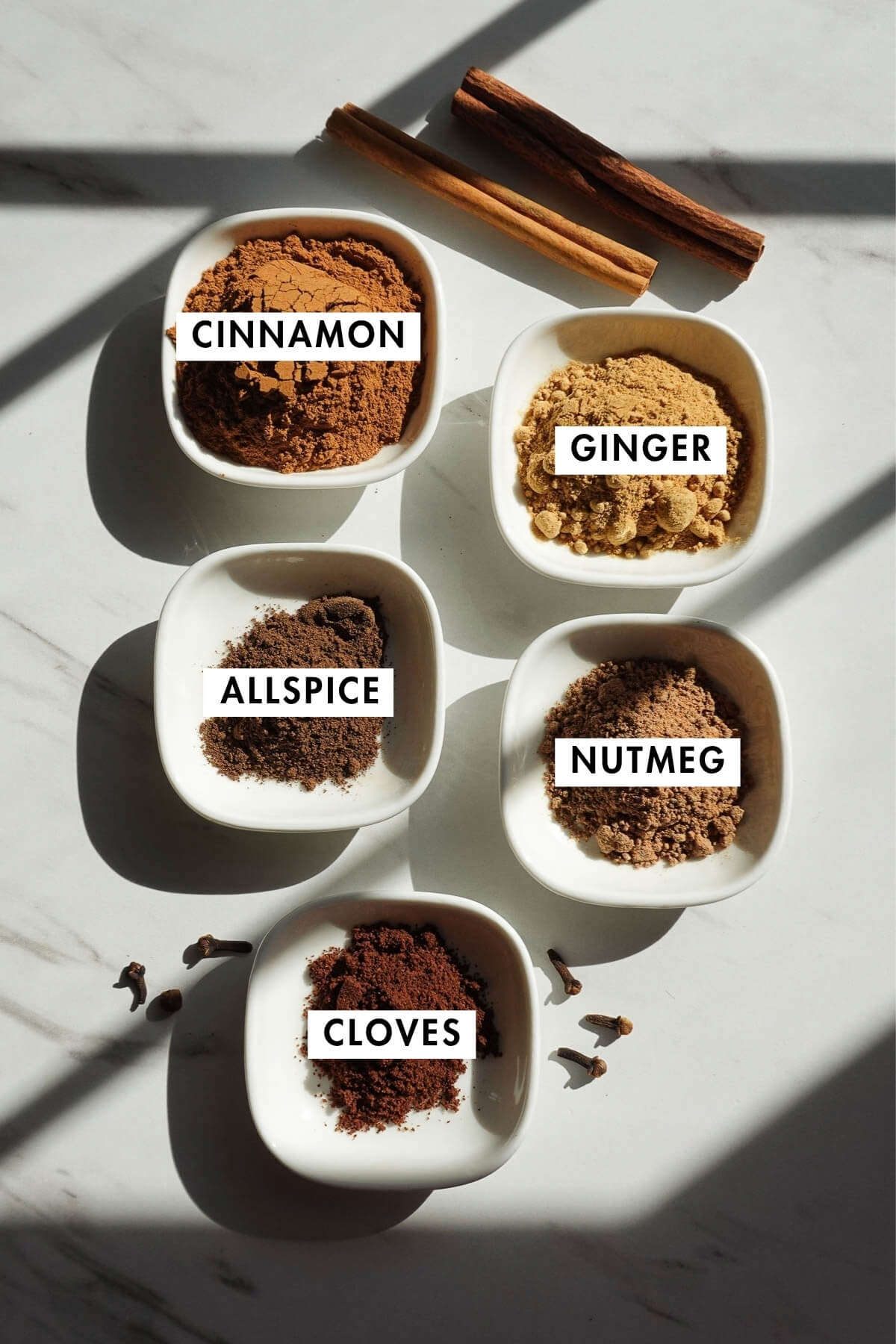 Spices used to make homemade pumpkin pie spice including cinnamon, nutmeg, ginger, allspice, and cloves.