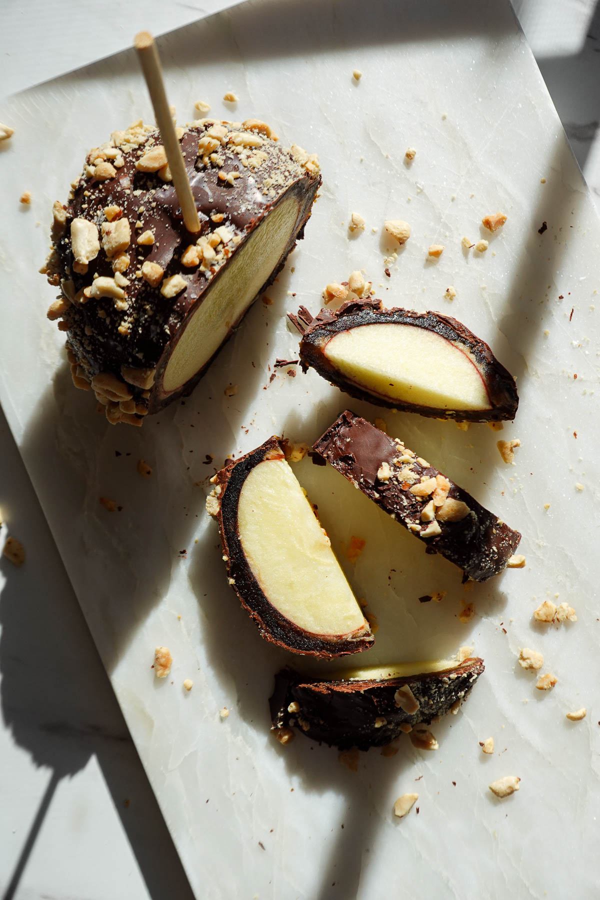 Date caramel apple slices showing crisp apple, a medjool date layer, and a chocolate shell.