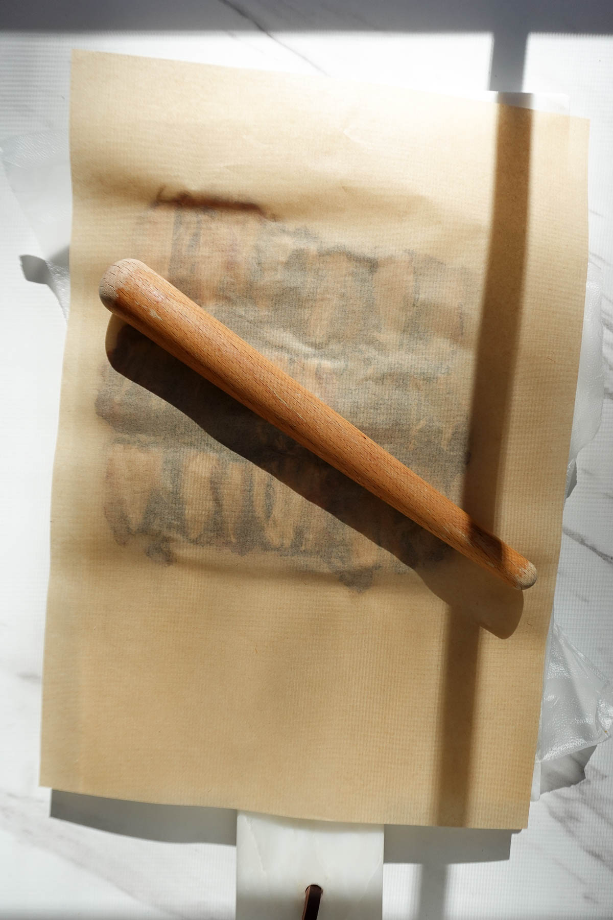 Rolling medjool dates into a flat layer beneath parchment paper.