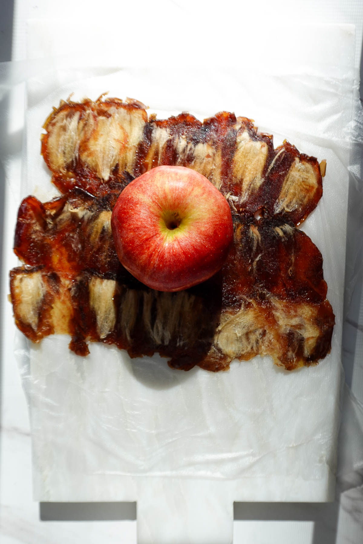 Whole apple centered on a flattened sheet of medjool dates.