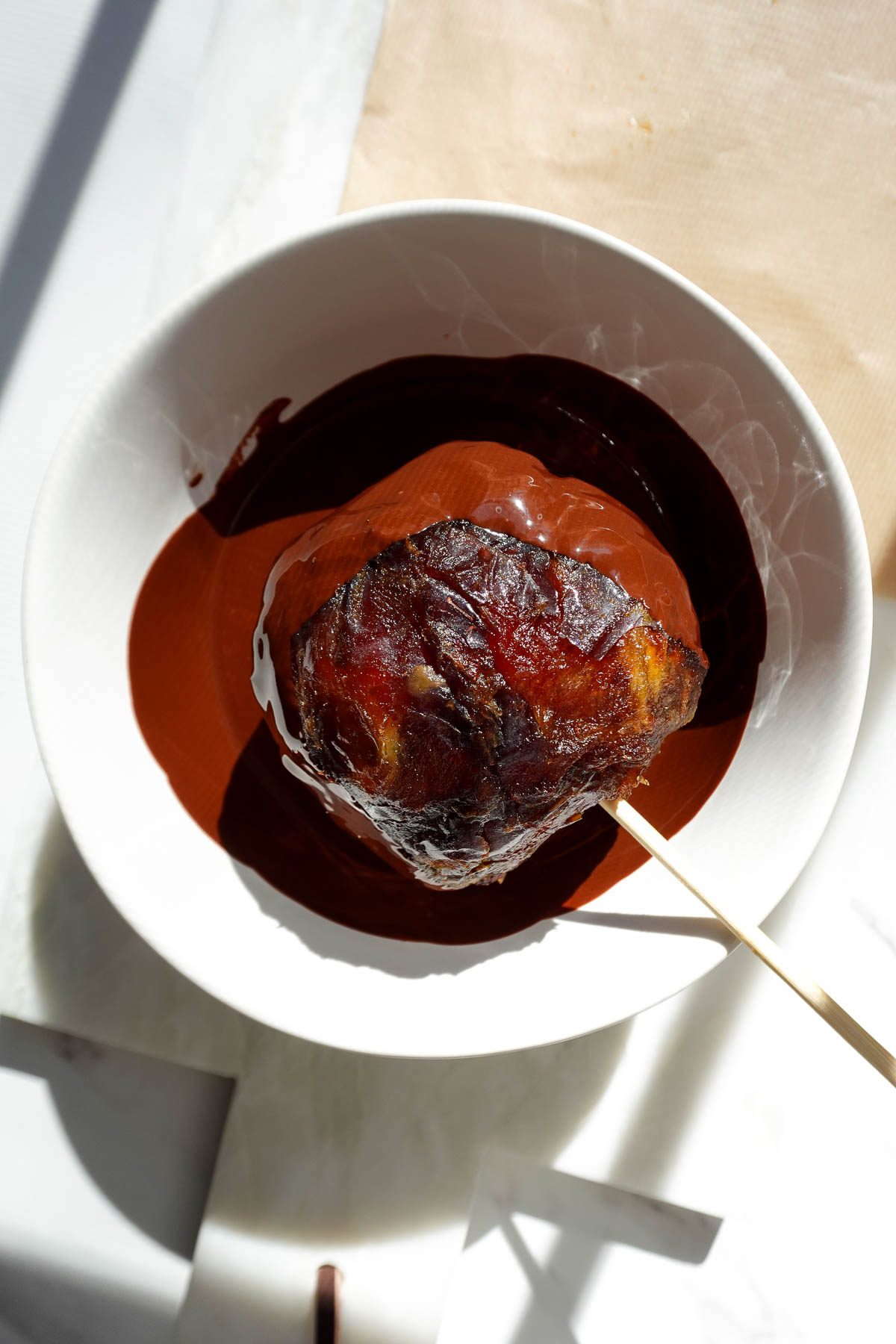 Dipping date-covered apple in a bowl of melted chocolate.