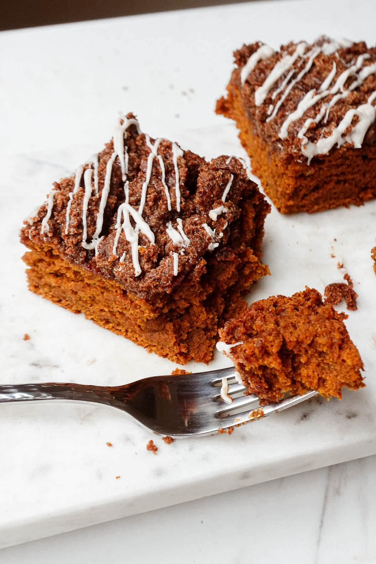 Vegan pumpkin coffee cake with a fork taking a bite out of it.