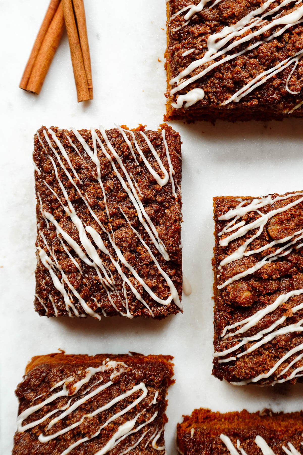 Slices of vegan pumpkin coffee cake topped with cinnamon-walnut streusel and vegan white chocolate drizzle.