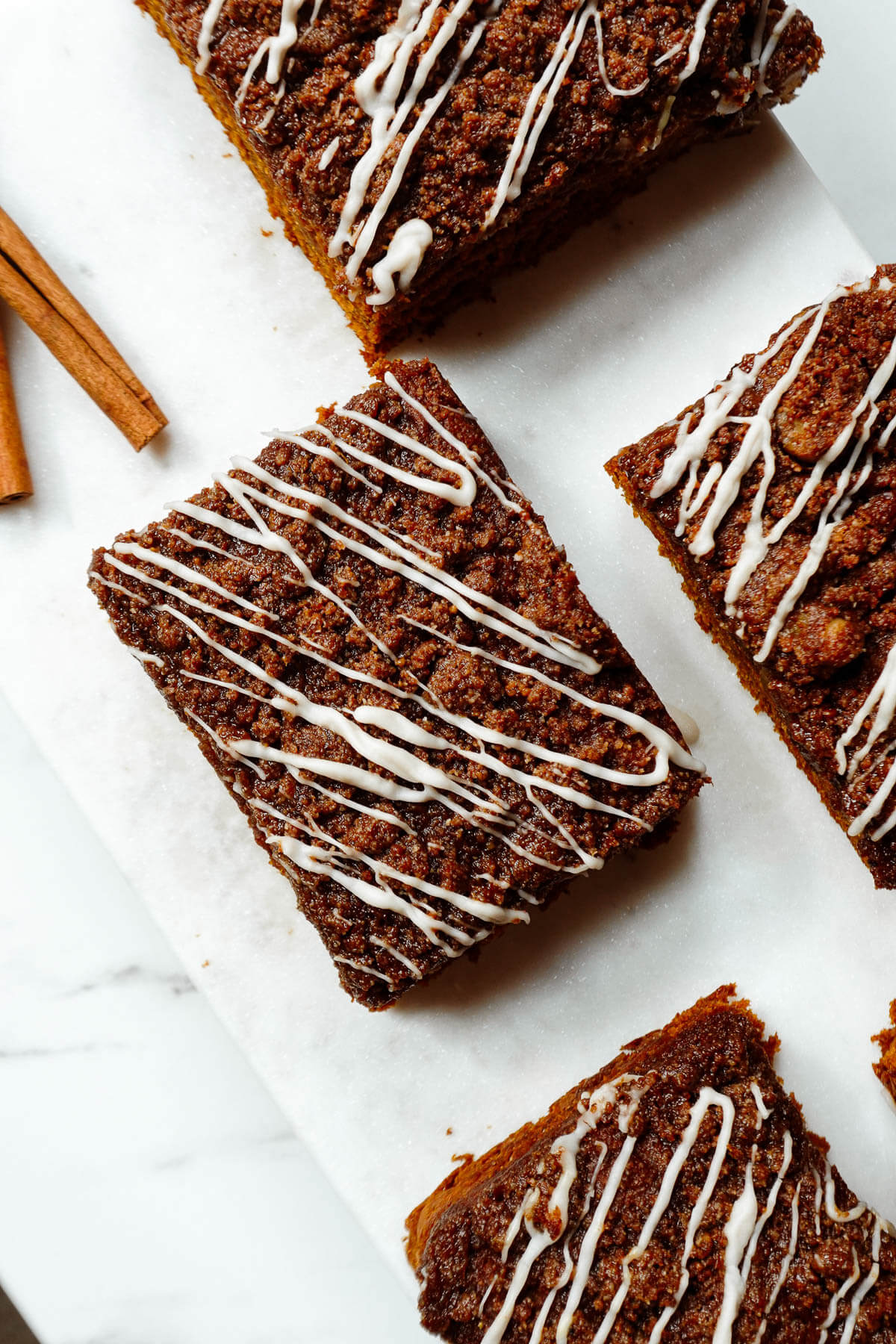 Slices of vegan pumpkin coffee cake topped with cinnamon-walnut streusel and vegan white chocolate drizzle.