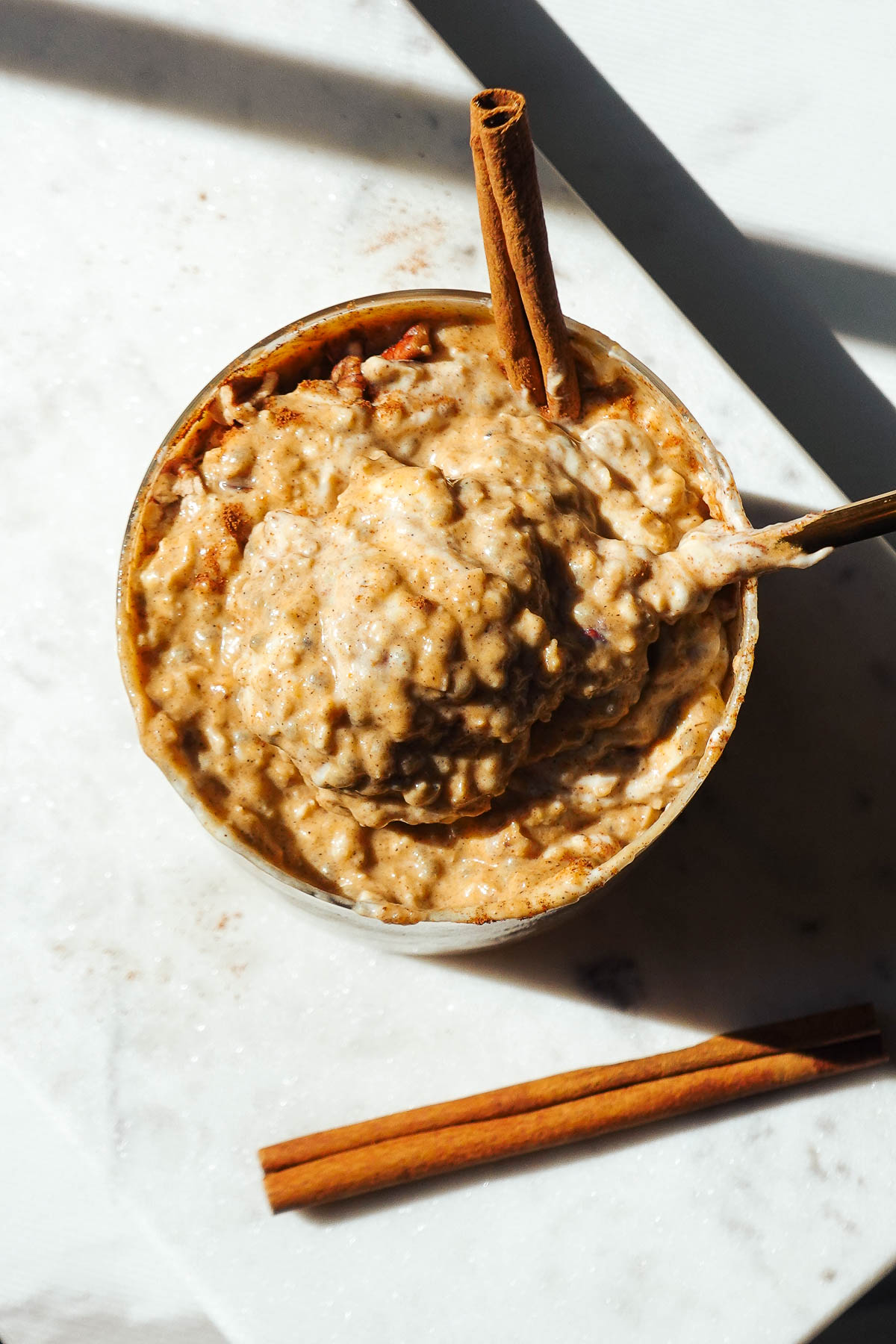 Pumpkin overnight oats in a glass jar with a spoon, showing the creamy texture.